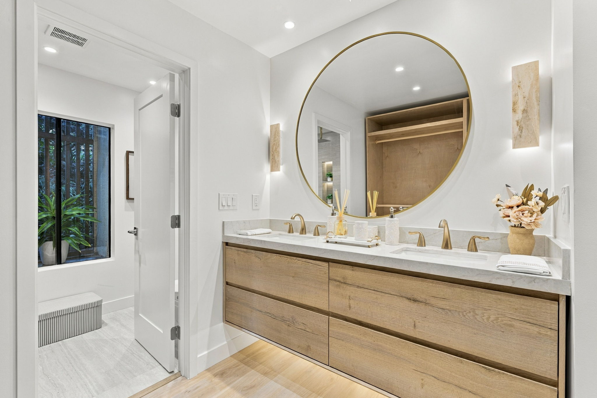 Bathroom vanity with a circular mirror and natural wood cabinetry